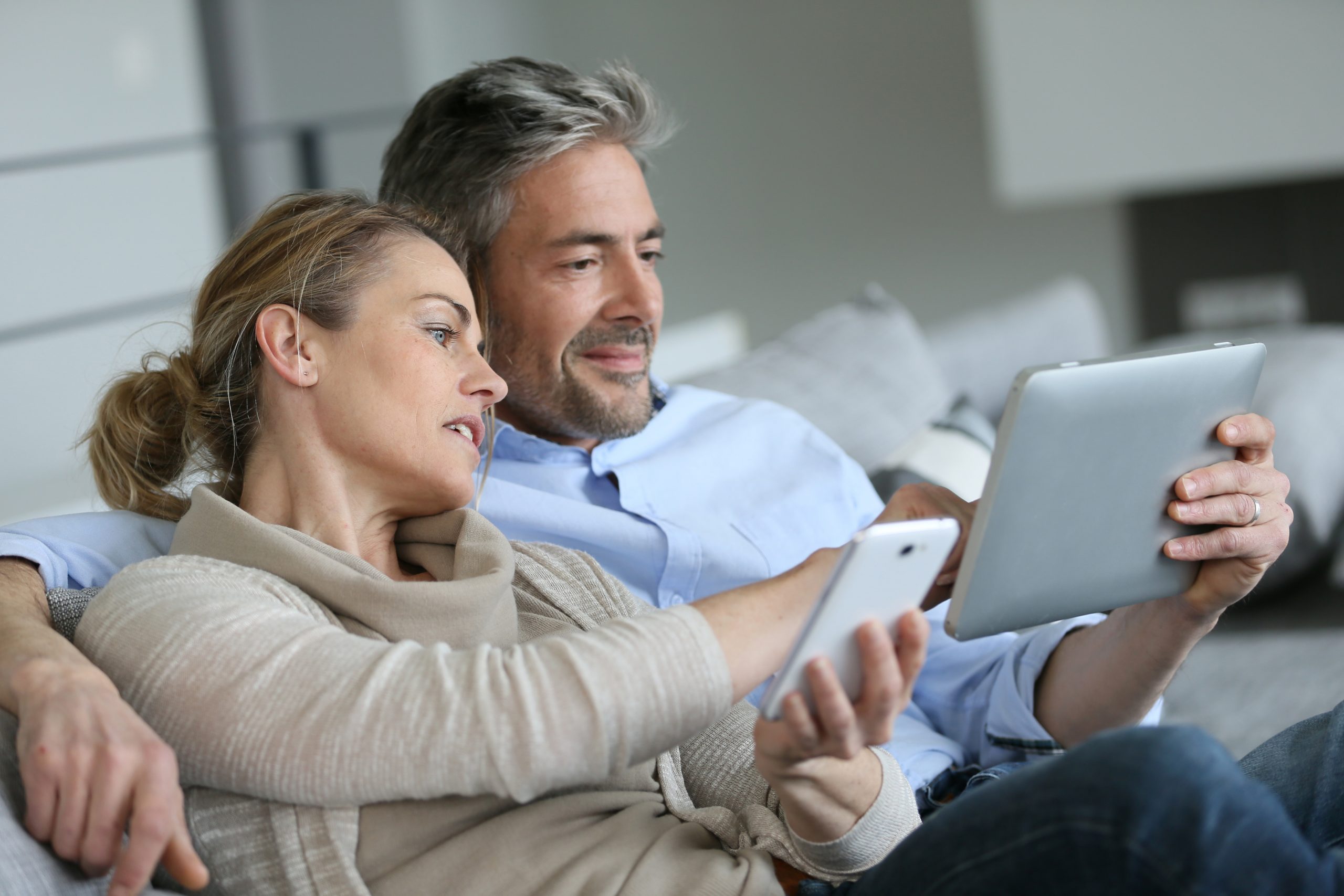 Couple assis dans un salon et regardant une tablette