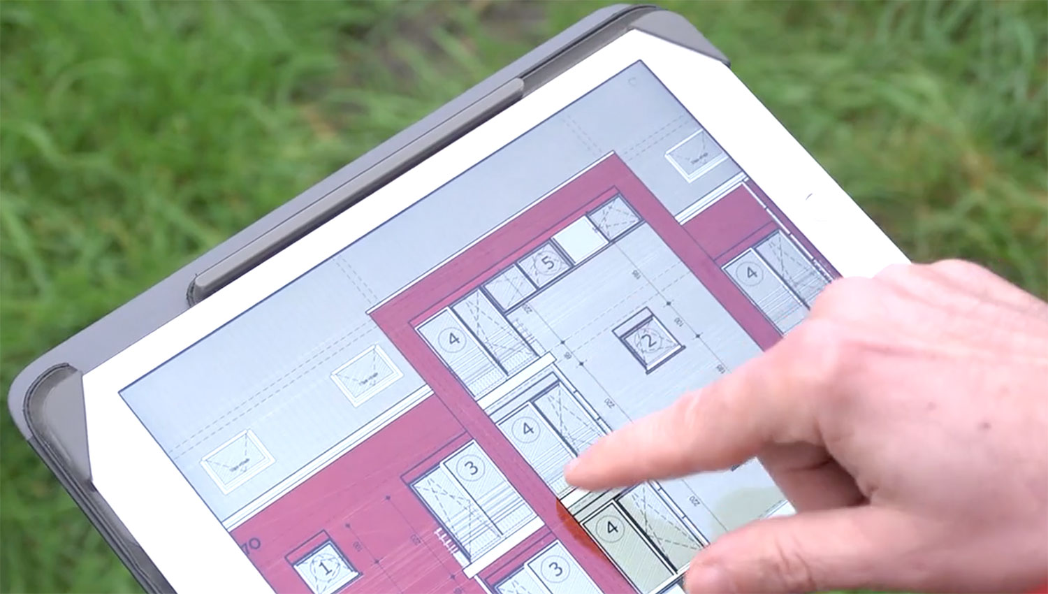 Main découvrant un plan d'implentation sur une tablette