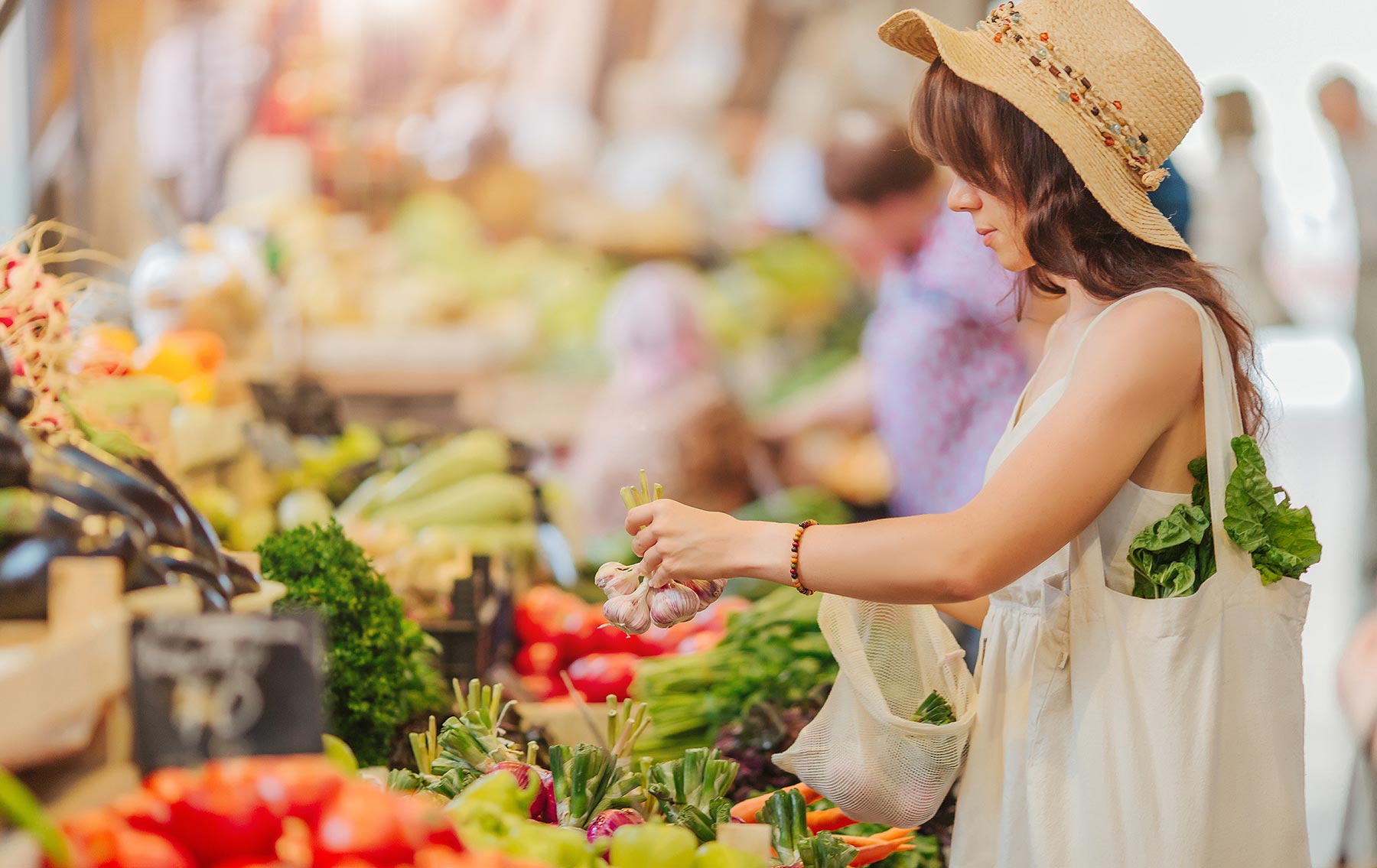 Jeune femme en train de regarder une étale de légumes sur un marché